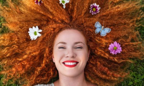A happy young woman lying down on green grass. Mental health concept